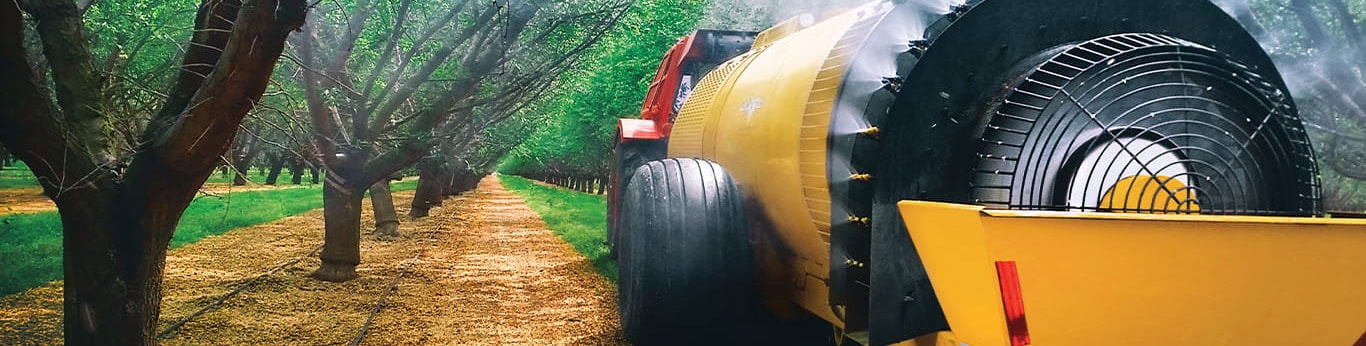 Orchard sprayer powered by a John Deere engine with a row of trees.