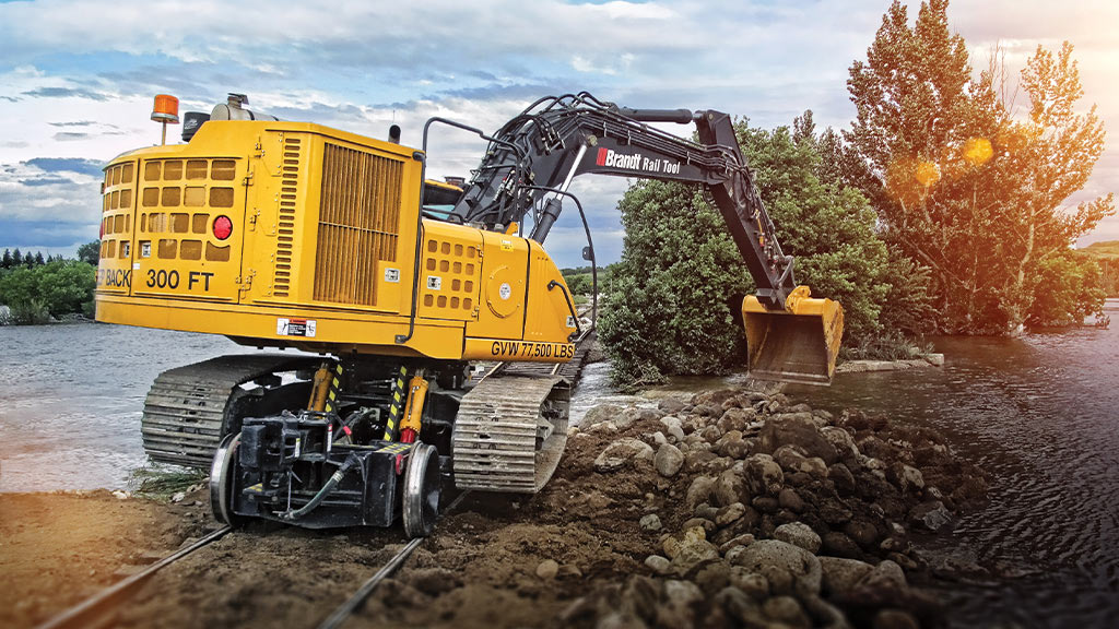 Brandt Rail Tools equipment scooping up rock in a stream powered by a John Deere industrial engine.