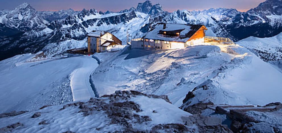 Cabins on a high mountain peak with bright lights turned on. 