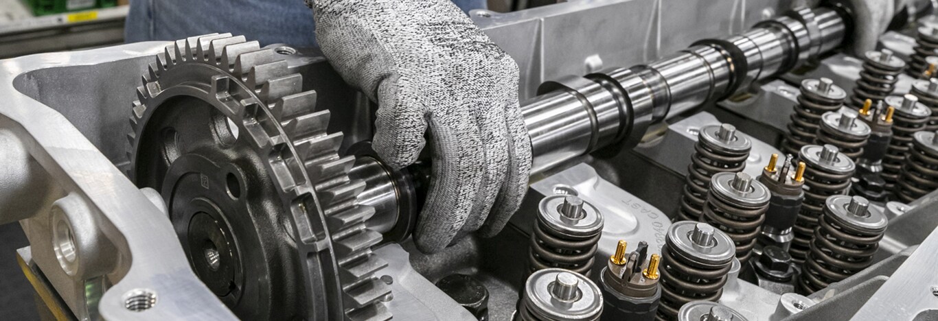 Gloved hand reaching into the body of an engine to perform maintenance