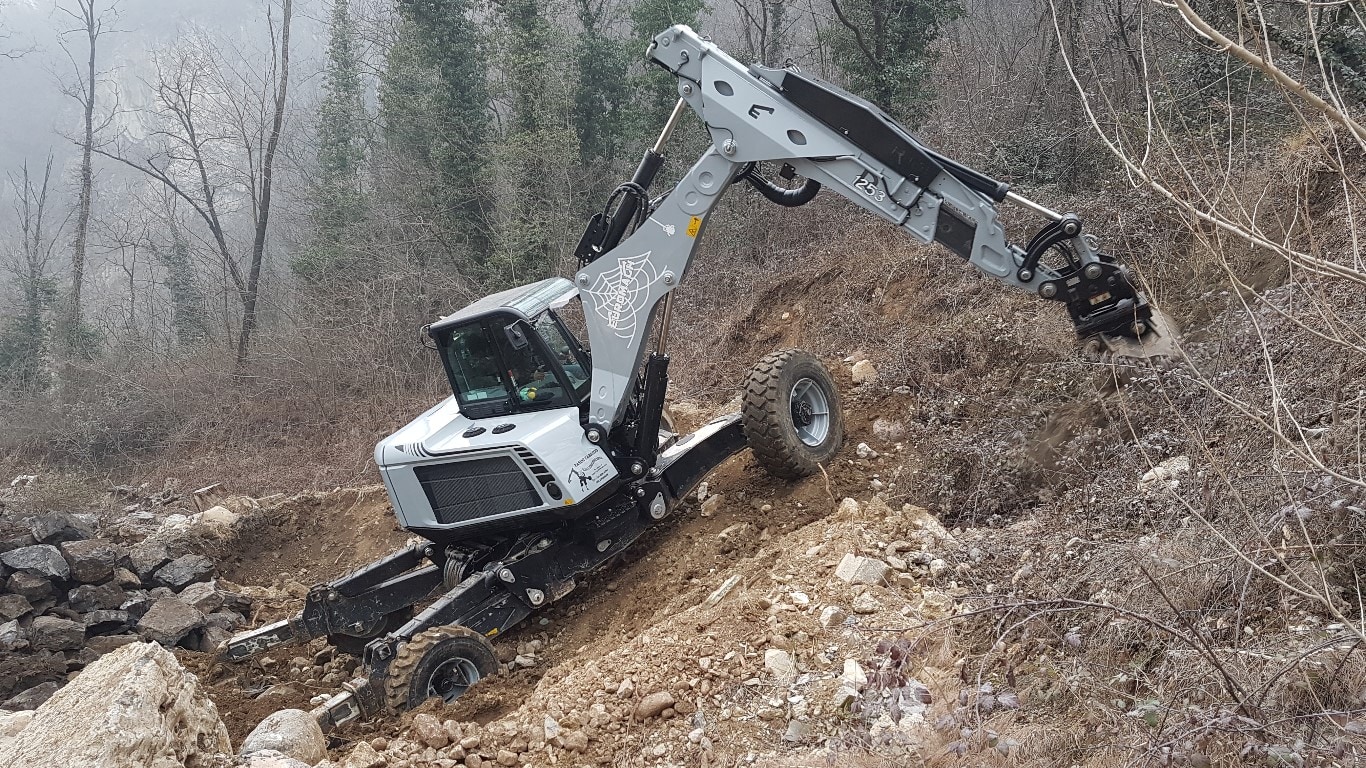 A John Deere-powered Euromach R1255 spider excavator working on the side of a rocky ravine.