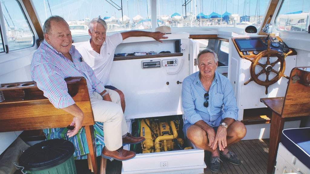 Three Co-Owners Sitting In Front of John Deere Marine Engine on Their Boat April
