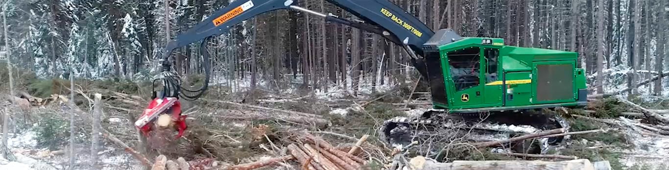 John Deere 959MH Tracked Harvester on a snowy day processing logs