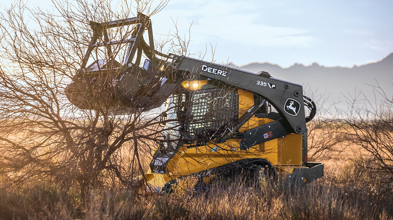 335 P-Tier compact track loader using a mulching head attachment to clear brush.