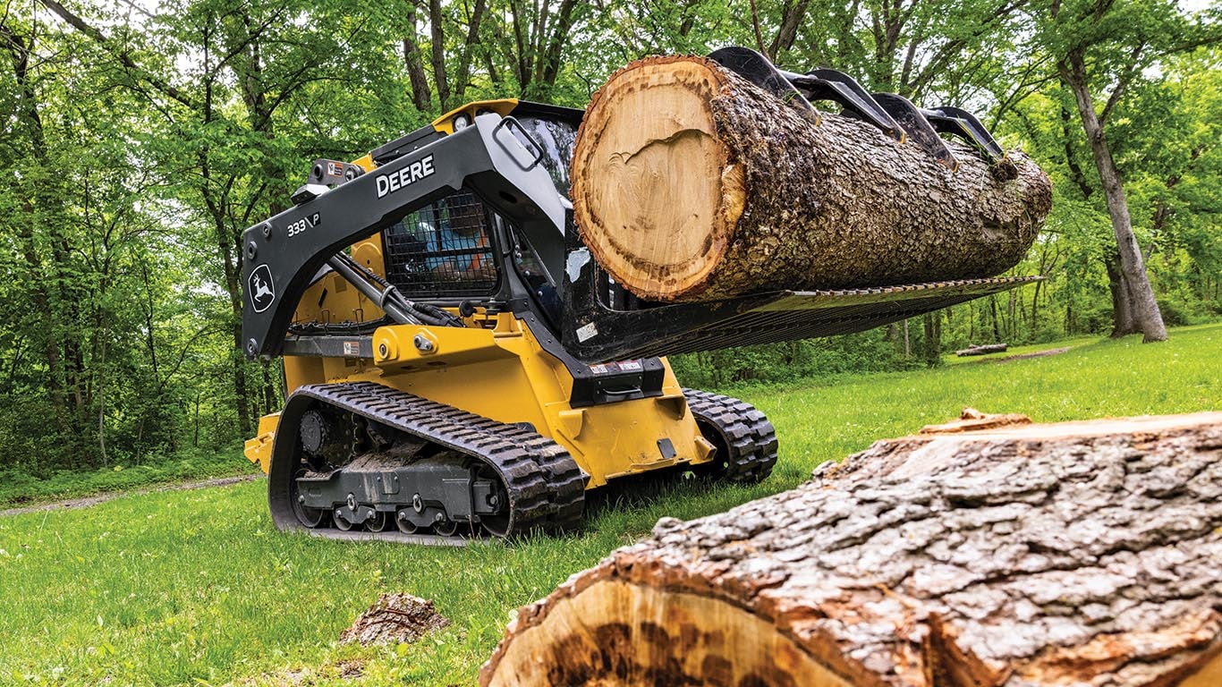 333 P-Tier compact track loader with a grapple attachment to lift a large log.