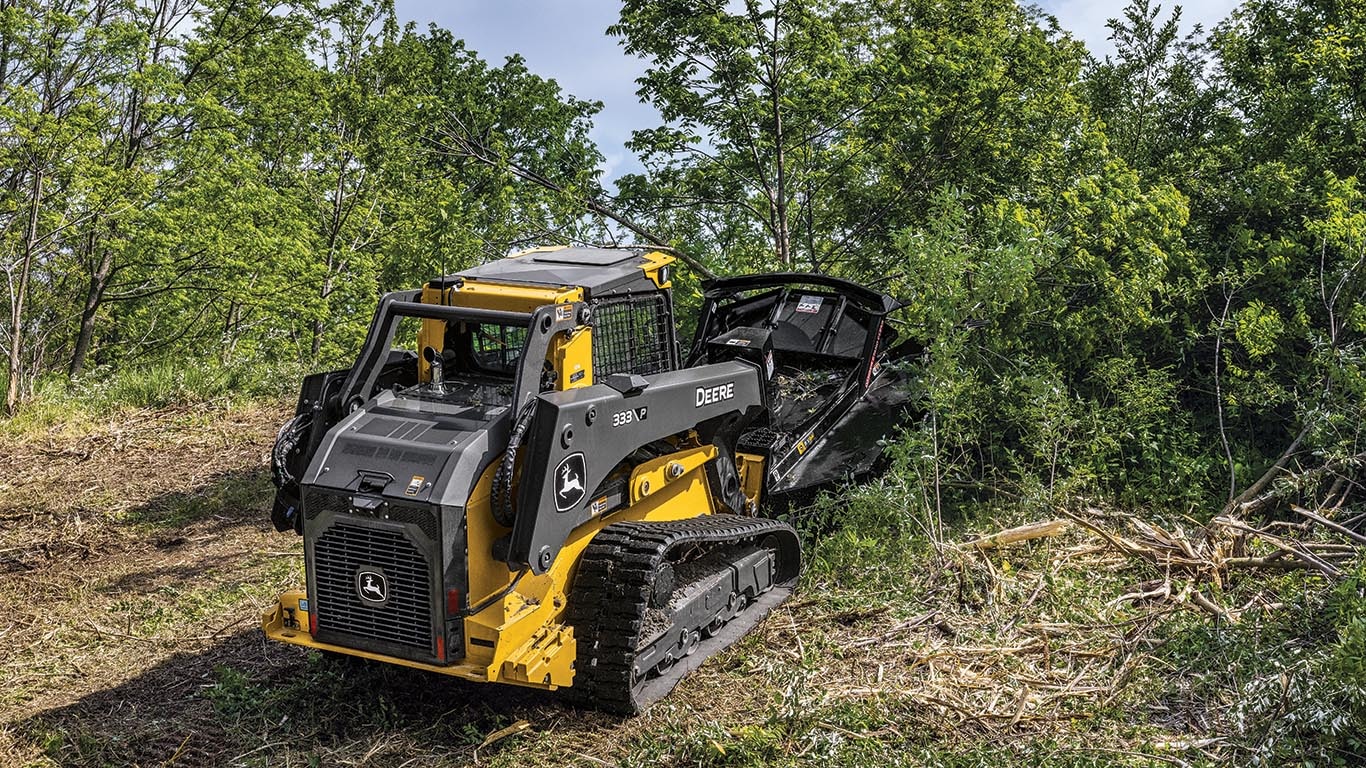 333 P-Tier compact track loader using a brush cutter to cut down small trees and brush.