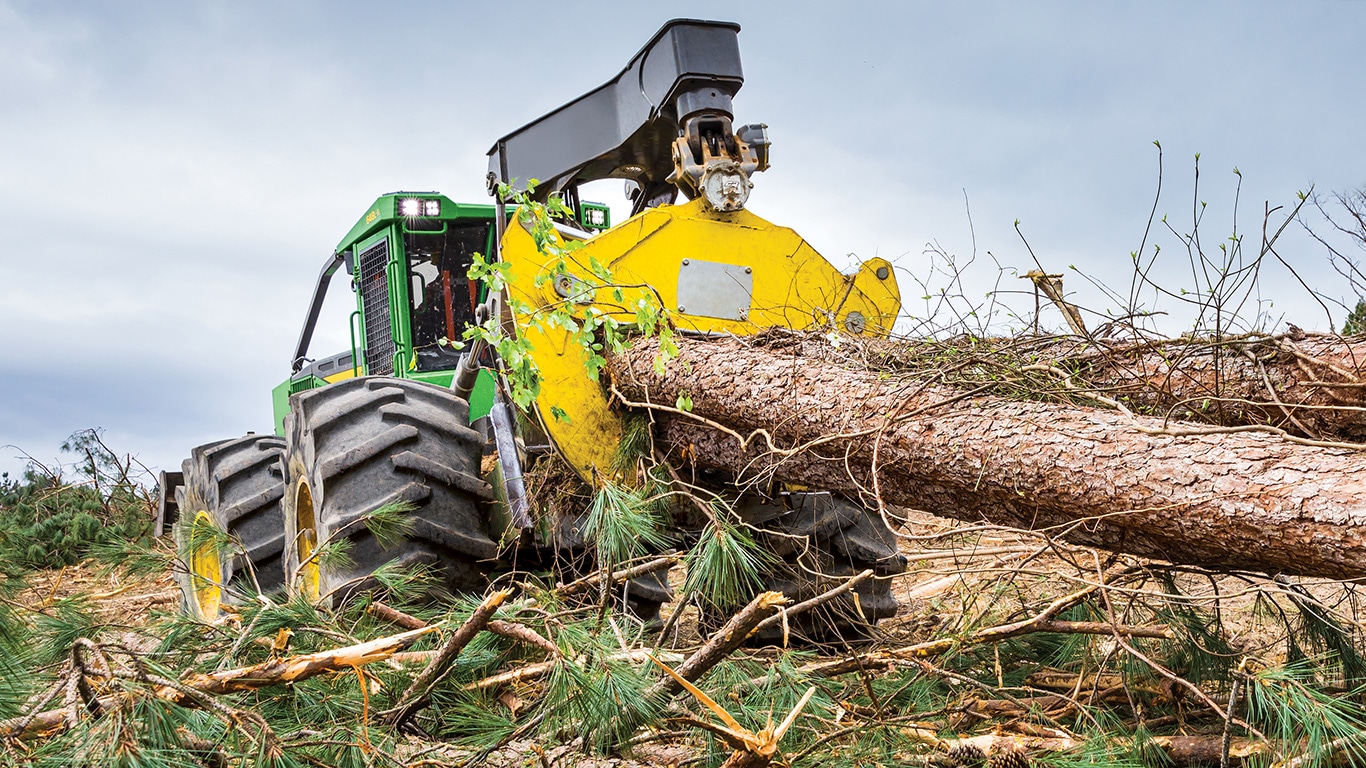 A John Deere 648L-II Grapple Skidder is dragging logs out of the forest to the landing site.