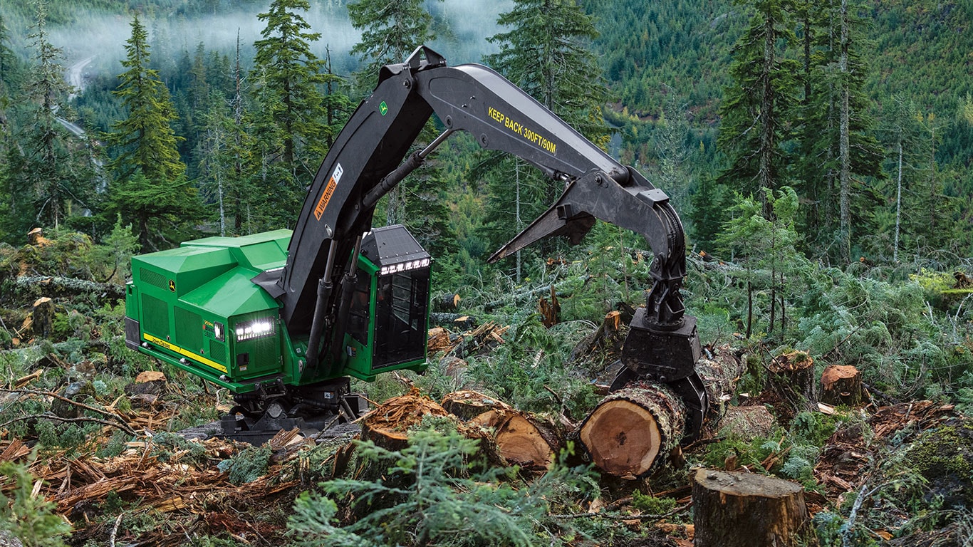 959ML Tracked Shovel Logger on the side of a steep hill grasping a large log to be moved