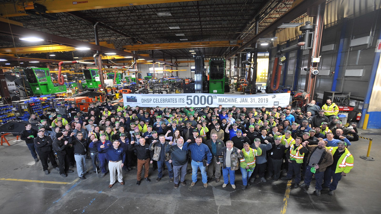 Factory workers gather around the 5000th forestry swing machine produced in Langley, British Columbia.