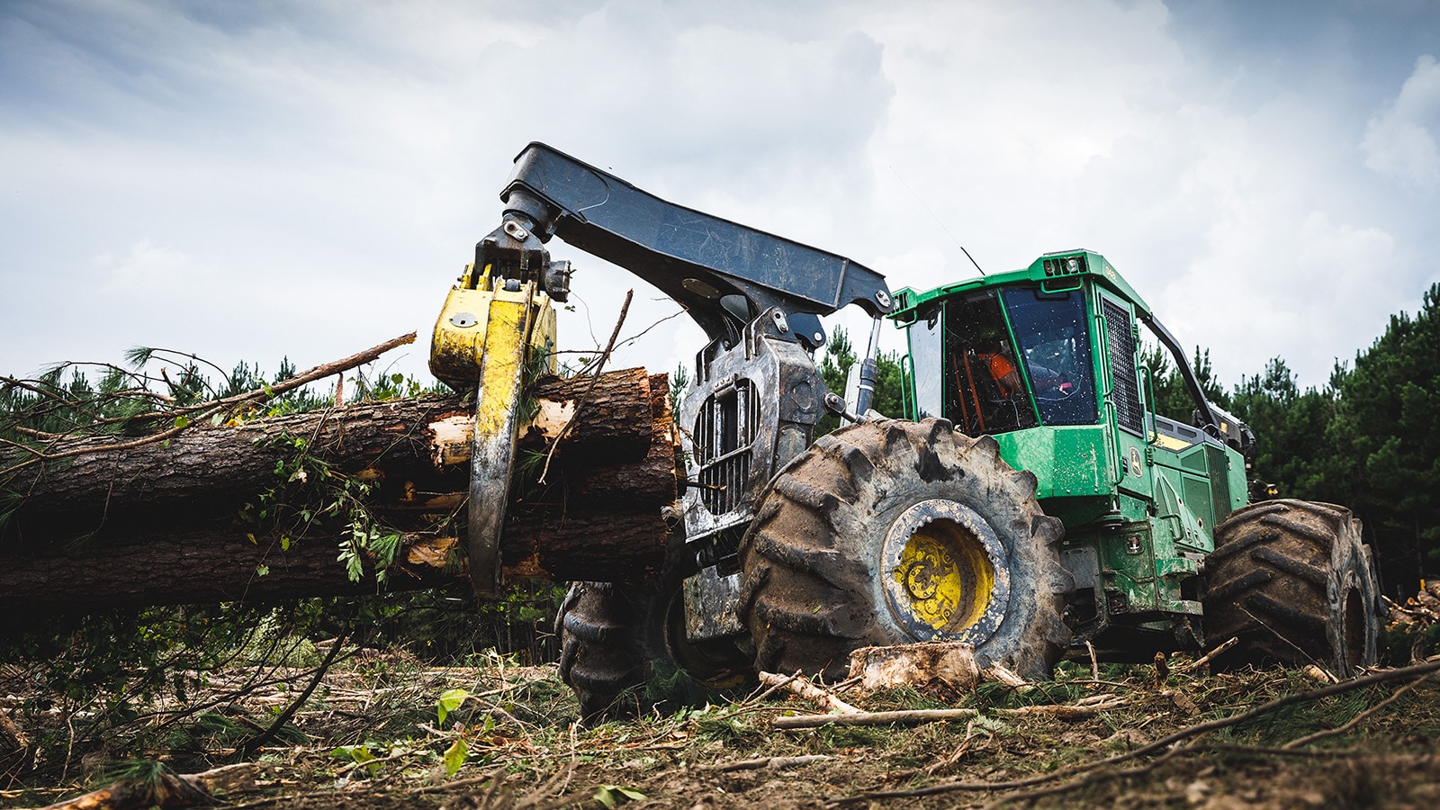 Skidder hauls logs at the landing with a dramatic sky in the background
