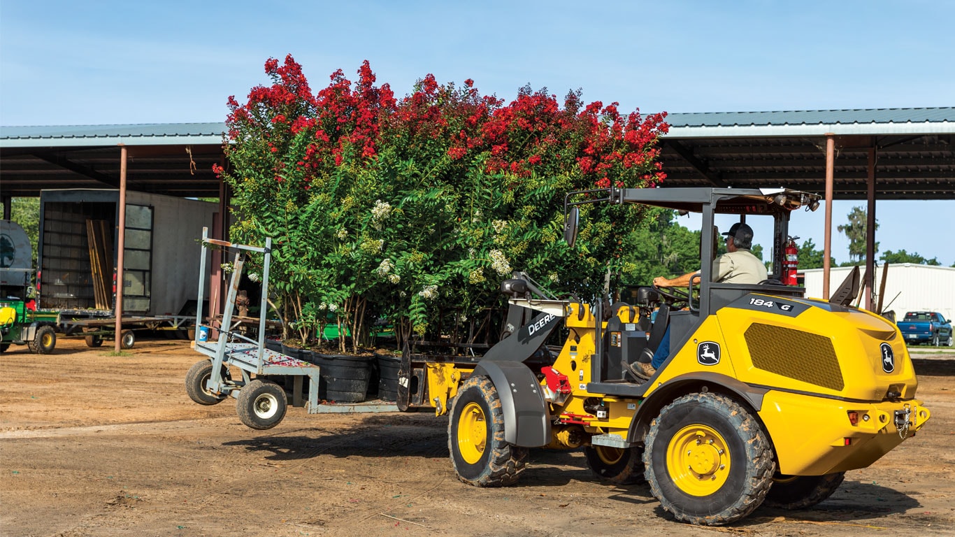 Image of the John Deere 184 G-Tier Compact Wheel Loader carrying trees 