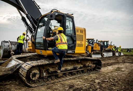 Man climbing into 245G excavator on jobsite