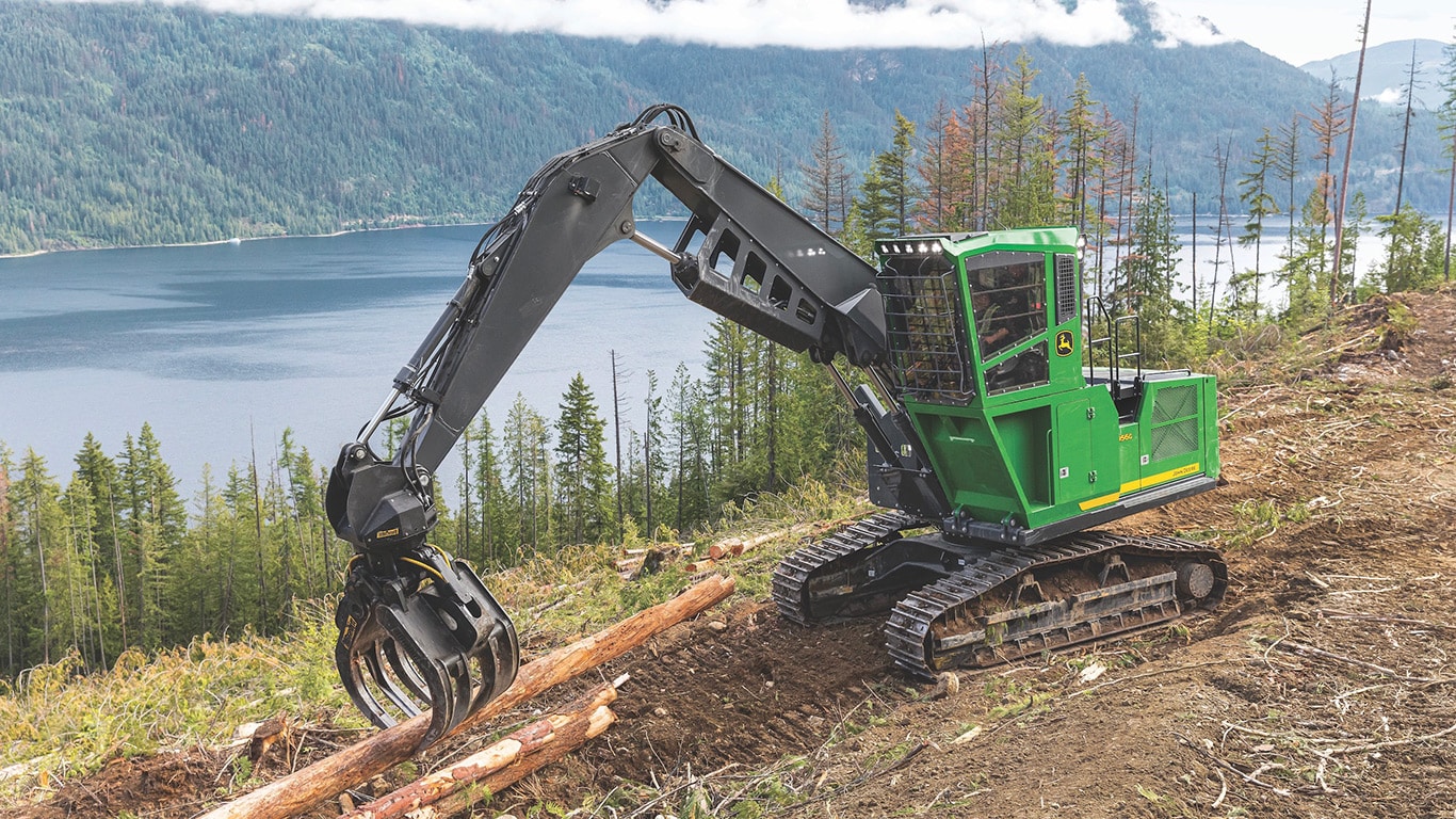 2956G crawler log loader picking up logs by the water