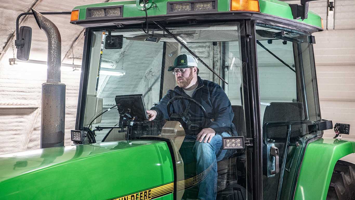 Man sitting in cab of tractor. 