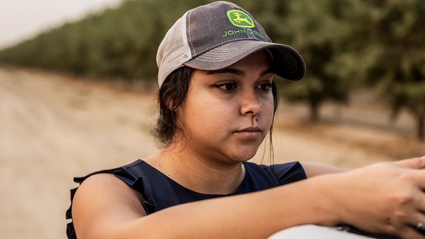 Woman standing next to truck outdoors looking at cell phone