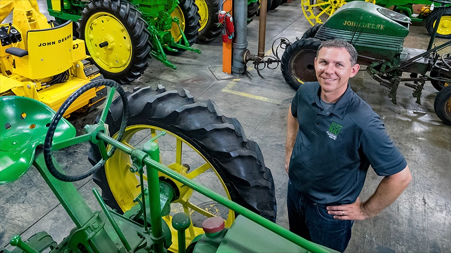 Neil Dahlstrom standing next to vintage John Deere tractors