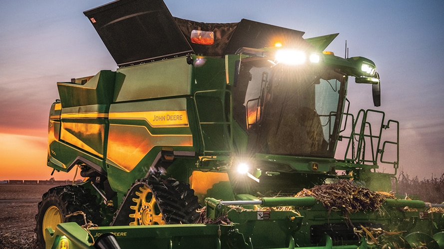 One of the new John Deere 9RX machines with lights turned on during sunset