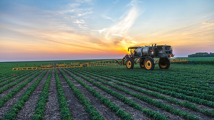 A long distance view of the newly announced John Deere 9RX series in a field at dawn