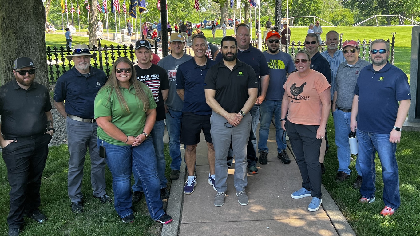 A large group of people pose in front of a United States veteran graveyard