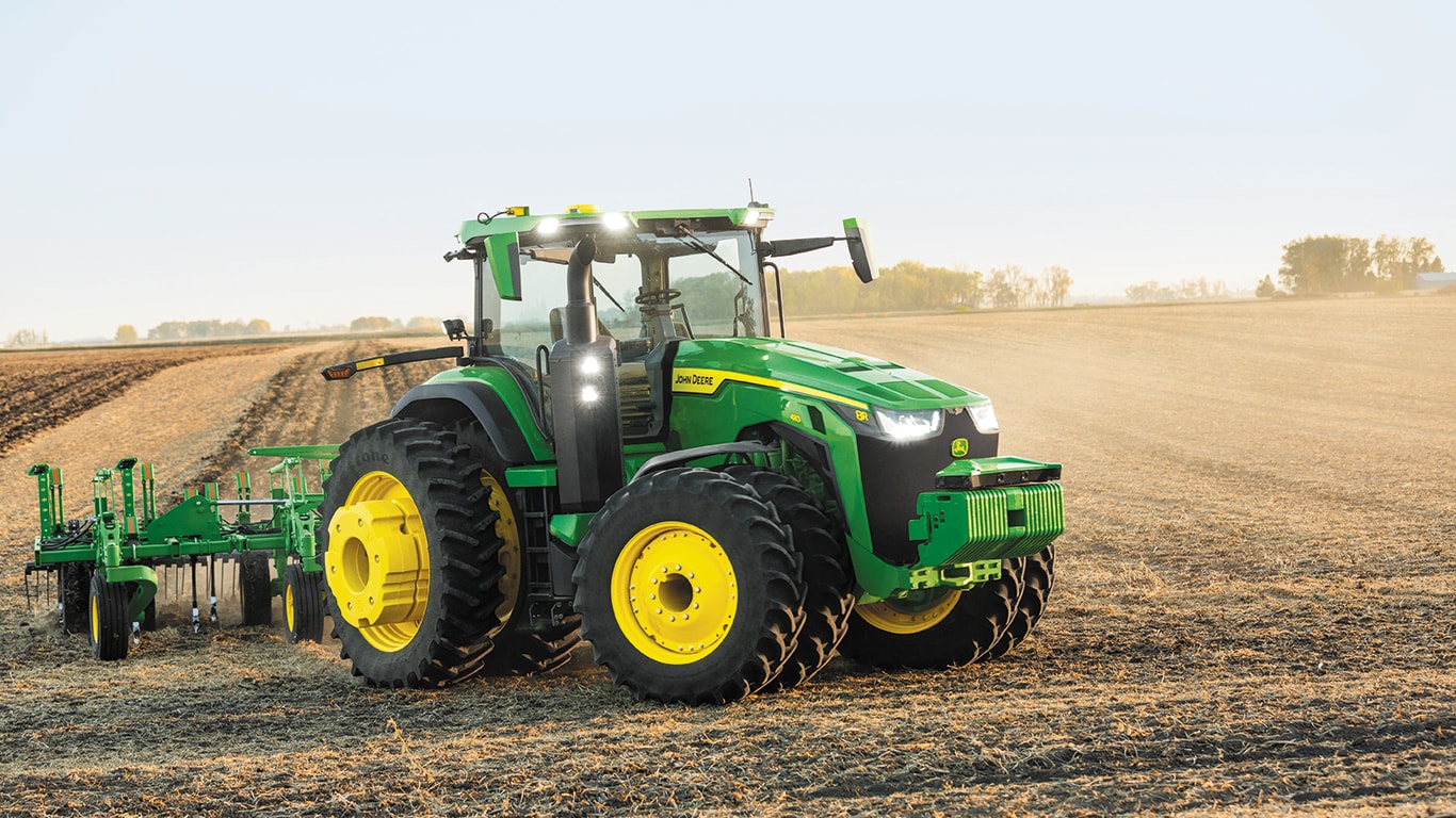 an autonomous 8R John Deere tractor tills a farm field