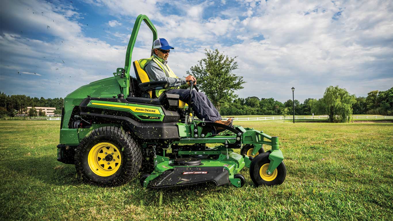 Action shot of debris flying in the air from an operator mowing grass with a John Deere Z997R ZTrak mower