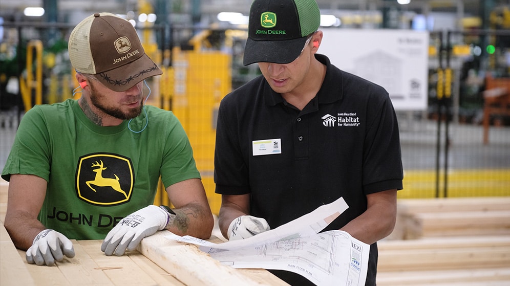 two Habitat volunteers look at building plans