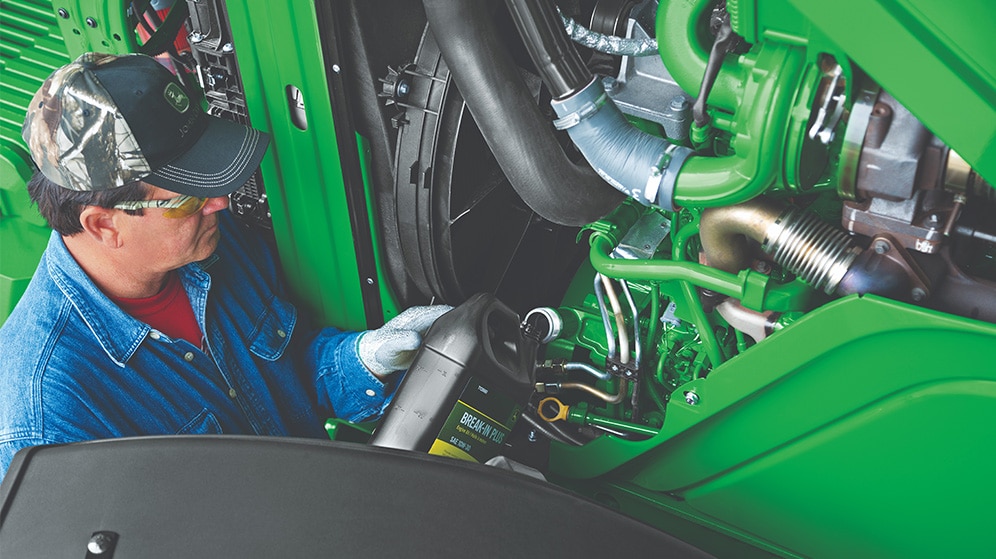 man fills fluid in a tractor