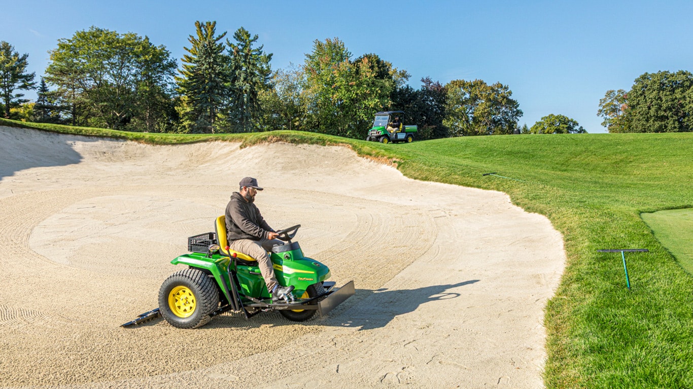 Utility tractor on a golf course sand bunker