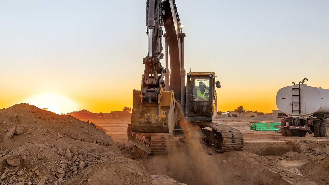 260 P-Tier excavator scooping dirt in front of a sunrise