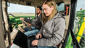 man and woman in cab of John Deere equipment