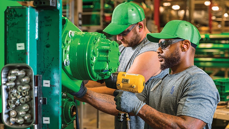Two men working together to build a John Deere agriculture product