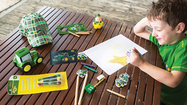 child drawing a green tractor with a crayon