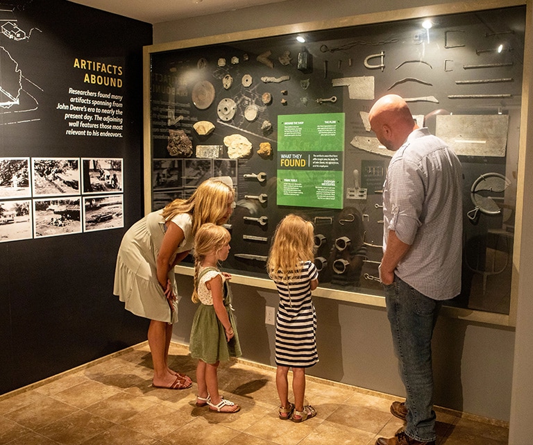 A family examining a wall of artifacts found at the site