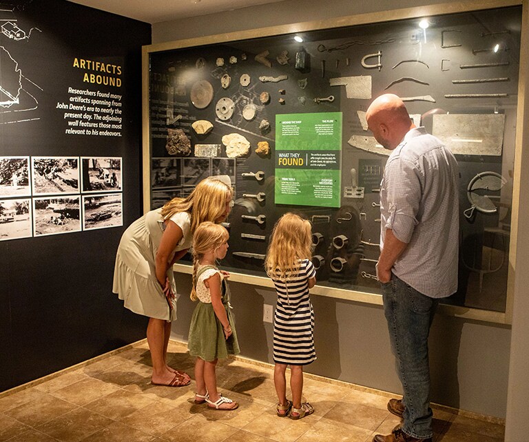 A family examining a wall of artifacts found at the site
