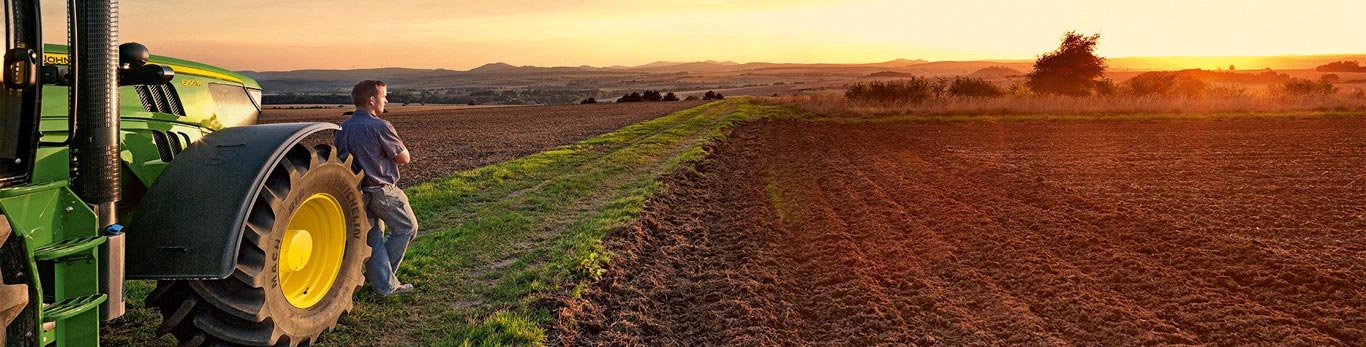 A man and his tractor on a farm during sunset