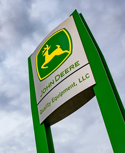 Looking up at the large John Deere green and yellow dealership sign
