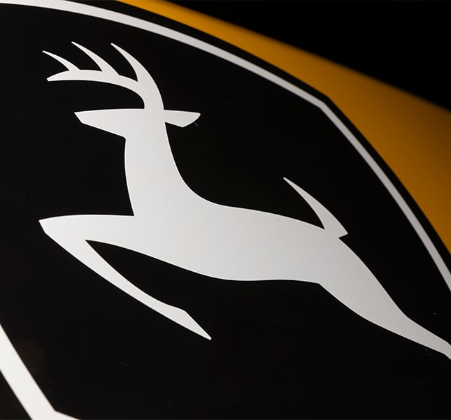 Close-up of the black John Deere leaping deer logo on a construction machine	