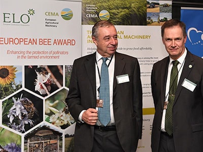 Two men in front of bee award backdrop