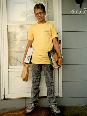 Young boy with school supplies in front of door