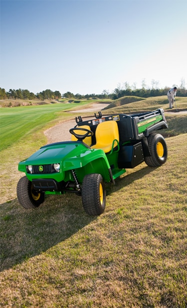 A John Series T-Series Gator utility vehicle parked next to golf course putting green