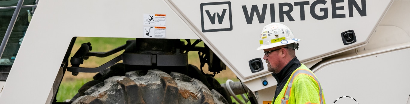 Machine operator inspecting his Wirtgen S-PAC WR 250i cold recycler and soil stabilizer at a job site