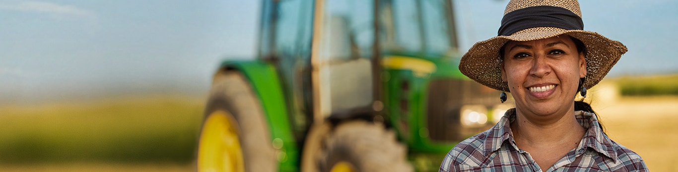 Female customer operator from Nuevo Leon, Mexico posing in front of her 6J Series tractor in a corn field