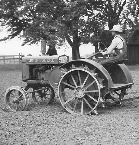Un Tractor Histórico John Deere "GP" de Uso General tira de un Rotocultivador John Deere Nº 7 en el campo