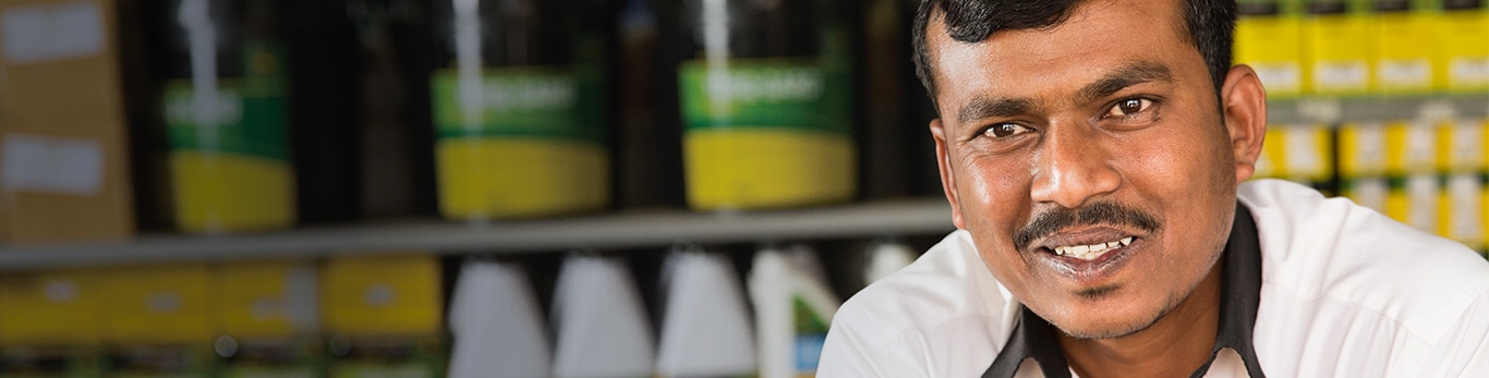 Parts manager in front of shelves of products at a John Deere Dealership located in Pune, India looking at the camera