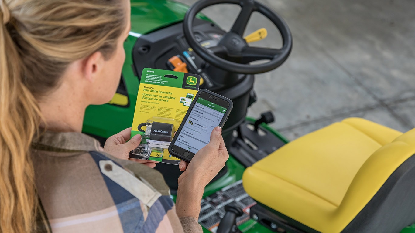 Woman holding a phone with the MowerPlus app open