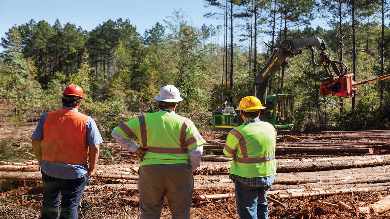 Image of loggers overseeing their jobsite and John Deere equipment at work