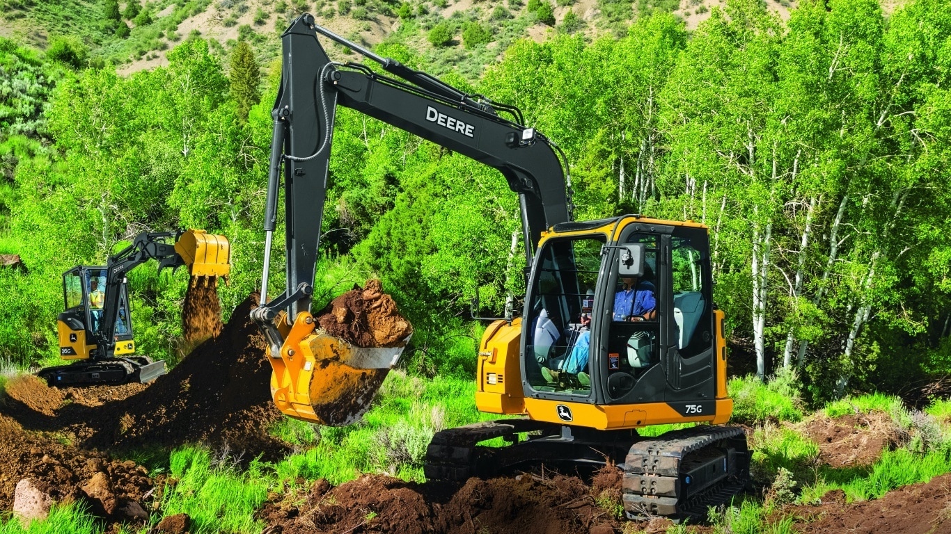 75G mid-size excavator and 26g mini excavator in the woods digging dirt with a bucket