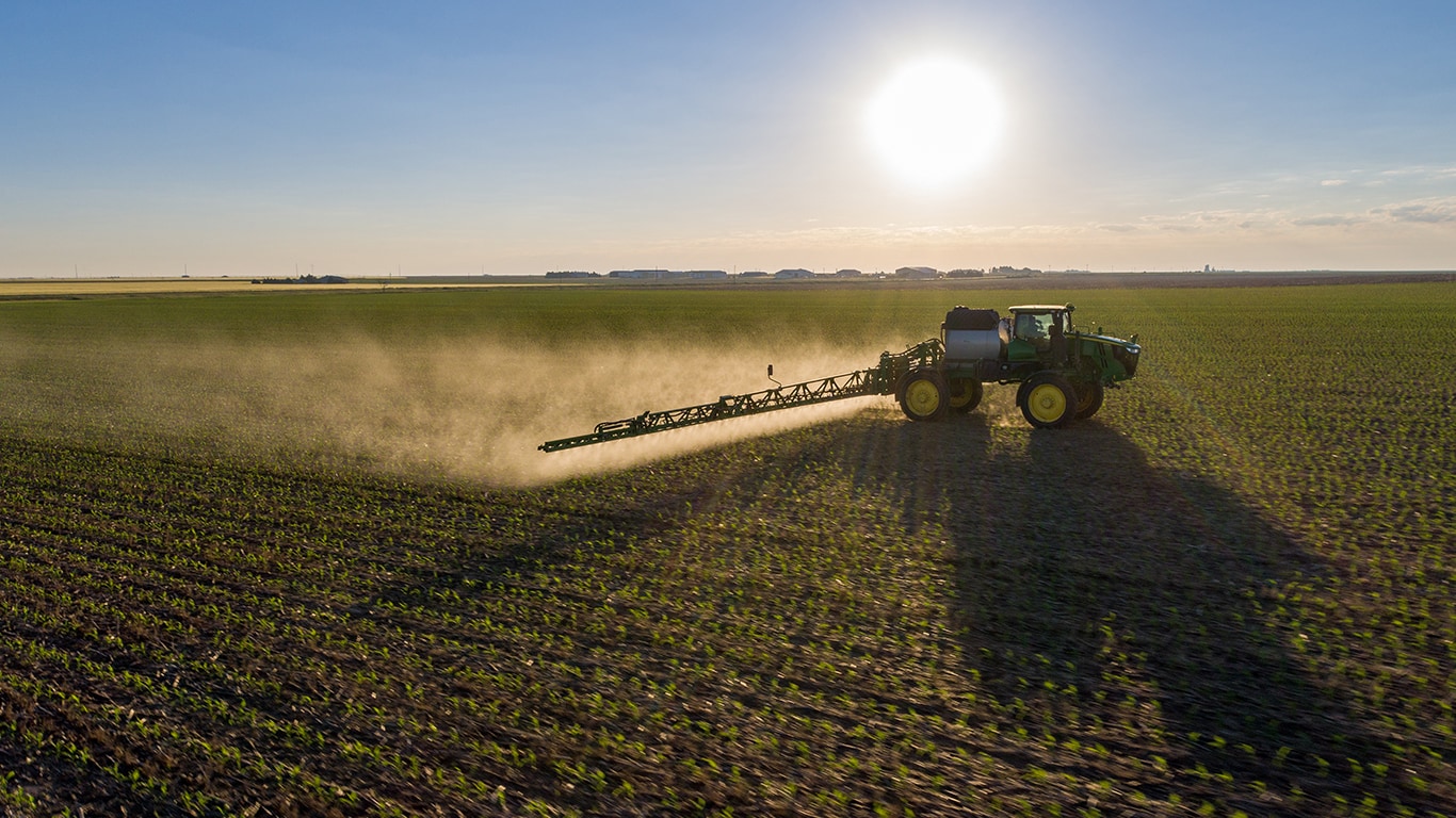 John Deere tractor and sprayer working in a field.