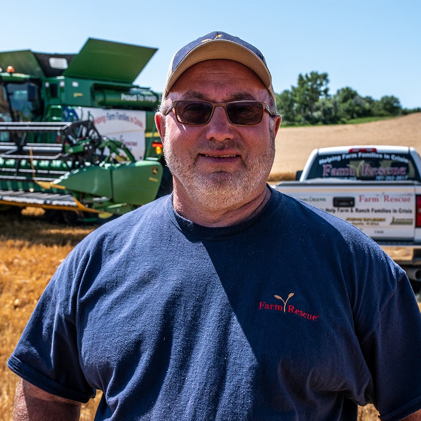 Larry Leier front and center with John Deere harvester in the back along with a Farm Rescue truck. 