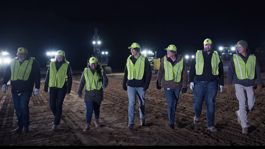 Several construction workers walk in a group together at night